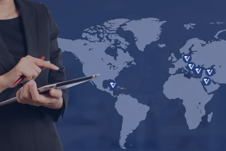 Business person holding a tablet in front of a world map with Vima markers